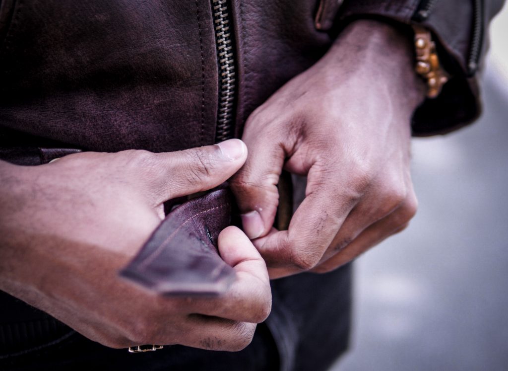 Close up of black hands buckling brown leather jacket. Straight To Hell Leather Jacket