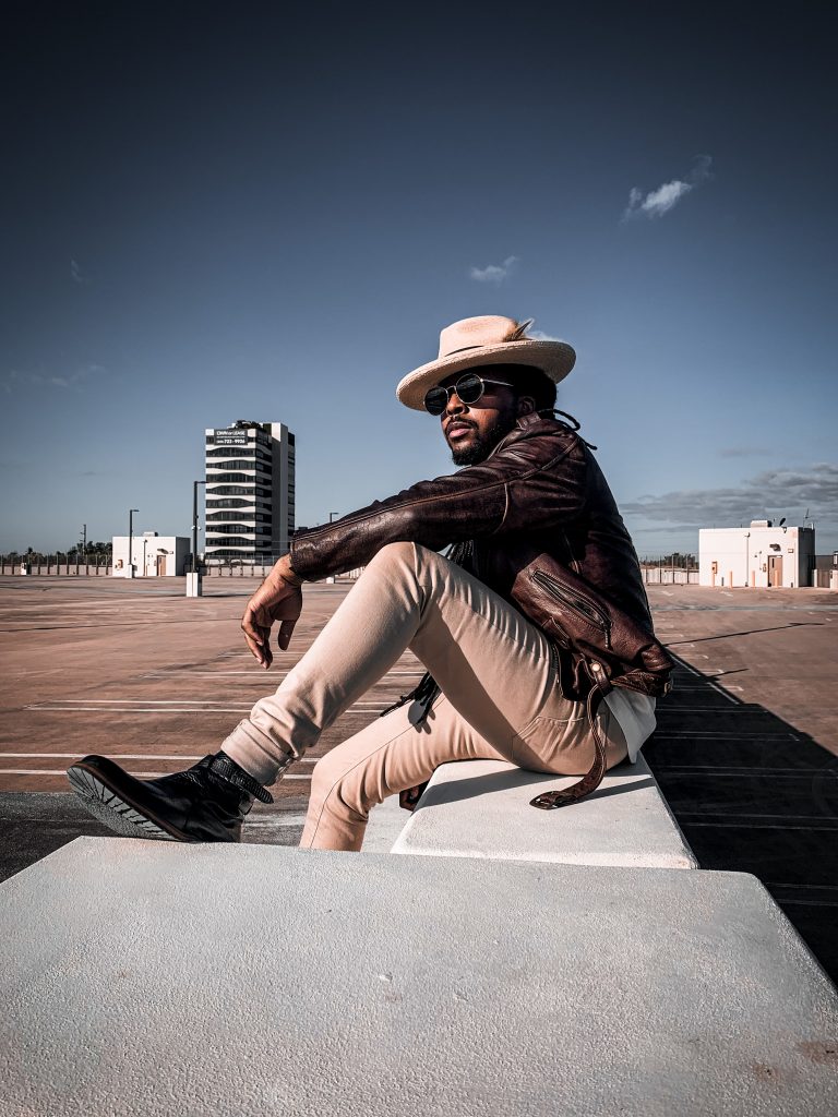 brown leather jacket, cream polo shirt with black chevron pattern, cream straw fedora, bone denim pants and black boots. 7 different ways to style Jodhpur boots!